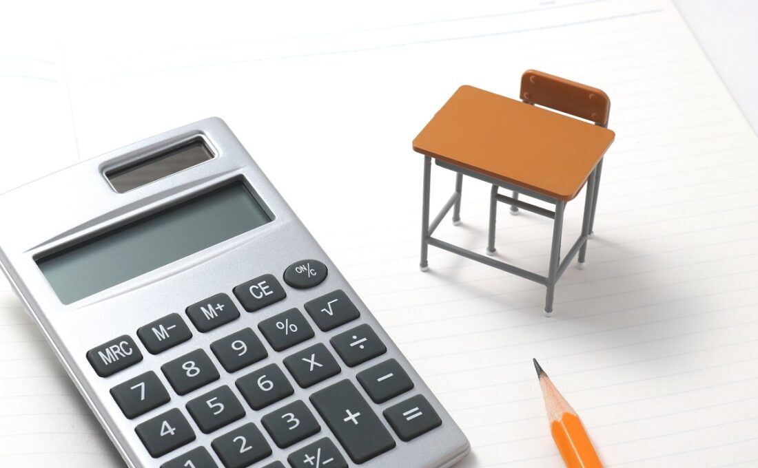 ノートに置かれた電卓と小さな机、鉛筆