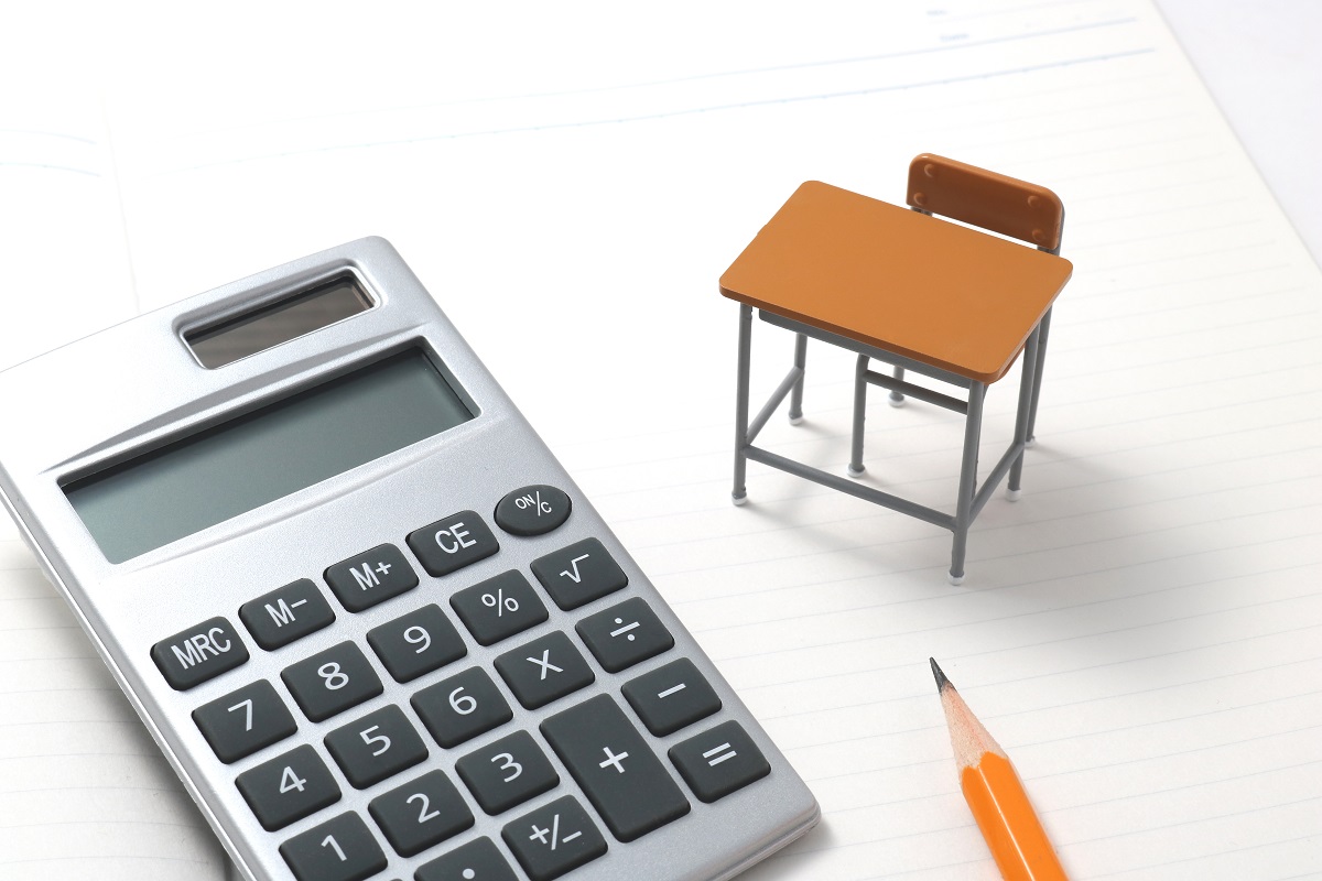 ノートに置かれた電卓と小さな机、鉛筆