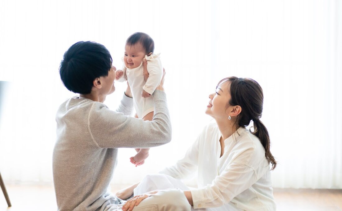 赤ちゃんを抱き上げる父親と笑顔の母親