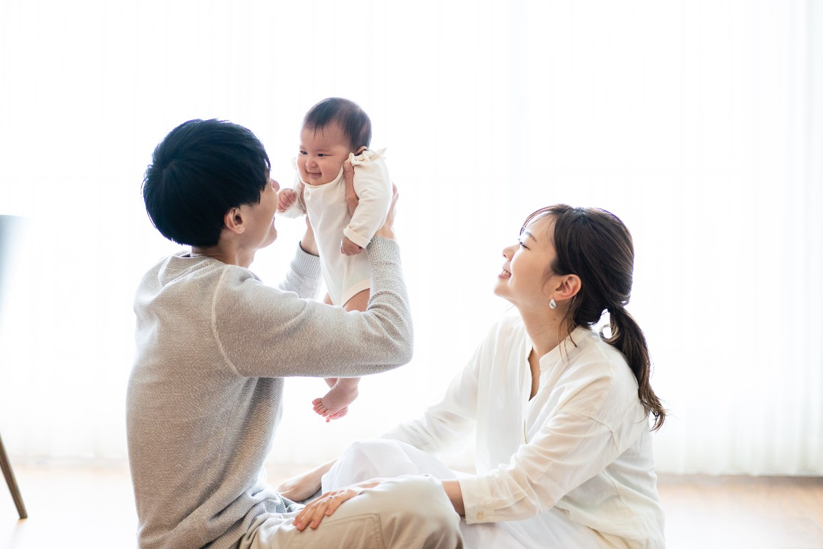赤ちゃんを抱き上げる父親と笑顔の母親