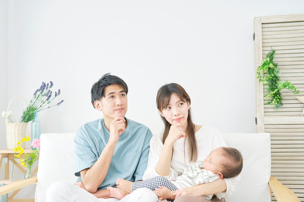 考え込む様子の若い夫婦と赤ちゃん。