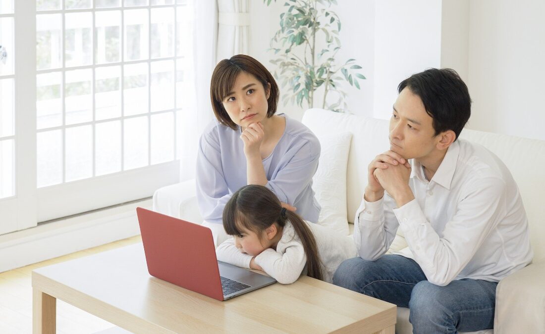 リビングルームでソファに座り、考え込む若い家族の姿。