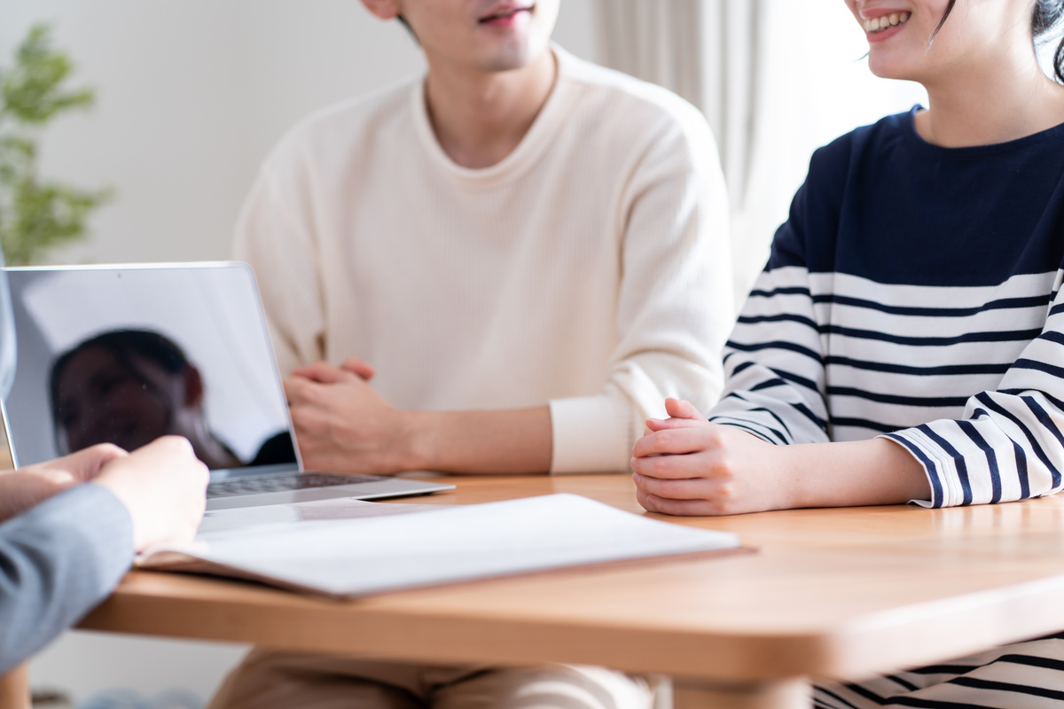 テーブルを囲んで、パソコンを前に話し合う二人の人々。