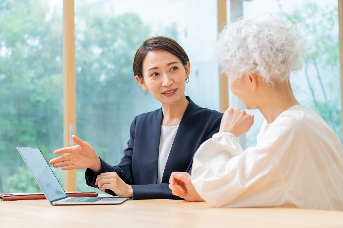 若い女性が年配の女性に対してパソコンを使って説明をしている様子。