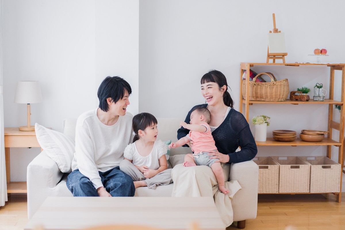 リビングルームでソファに座って笑顔で過ごす4人家族。
