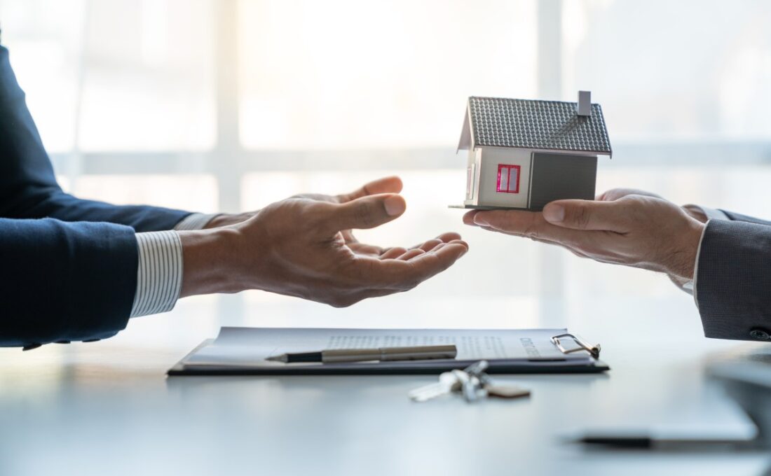 不動産の契約や譲渡を象徴する、ミニチュアの家を手渡すシーン。