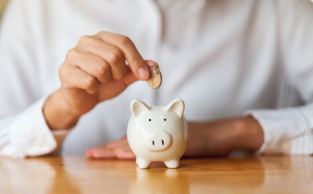 貯金箱にコインを入れる手。