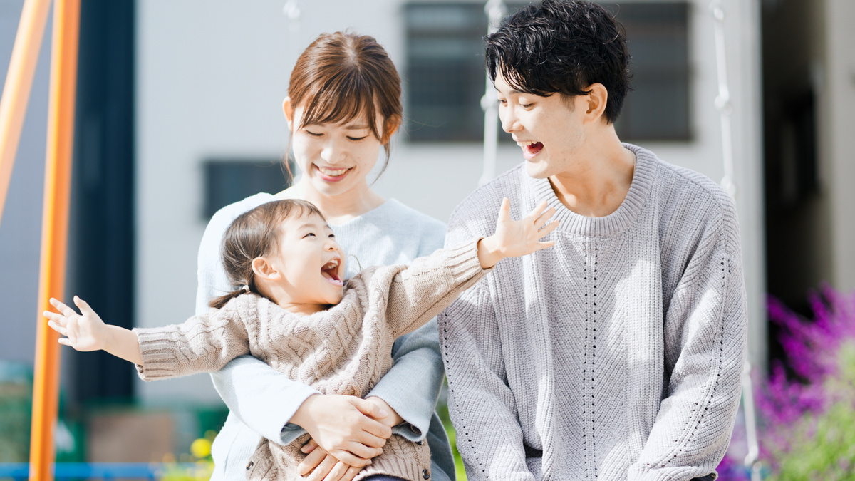 笑顔で公園に座る家族。両親と一緒に楽しんでいる子ども