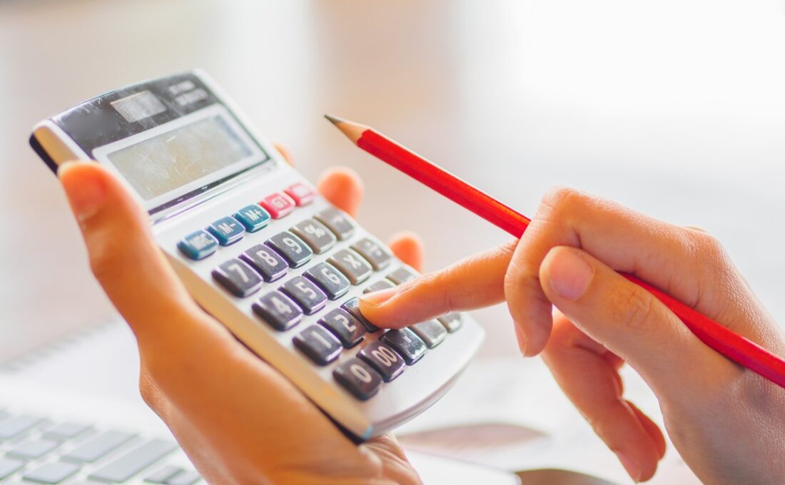 鉛筆を持ちながら計算機で計算をしている人物