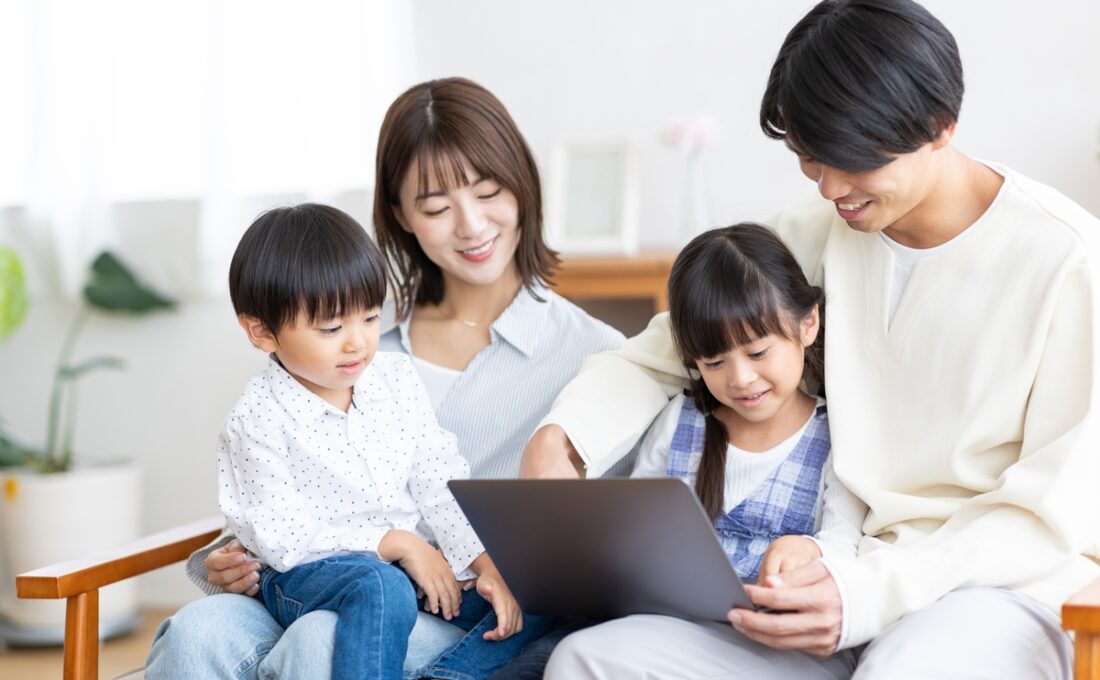 家族全員でパソコンを見ながら過ごす笑顔の家族
