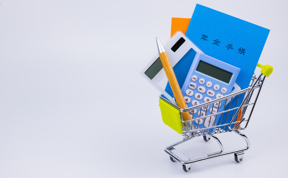 小さなショッピングカートに入った年金手帳、電卓、ペン