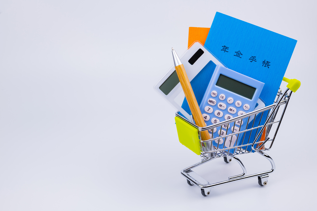 小さなショッピングカートに入った年金手帳、電卓、ペン