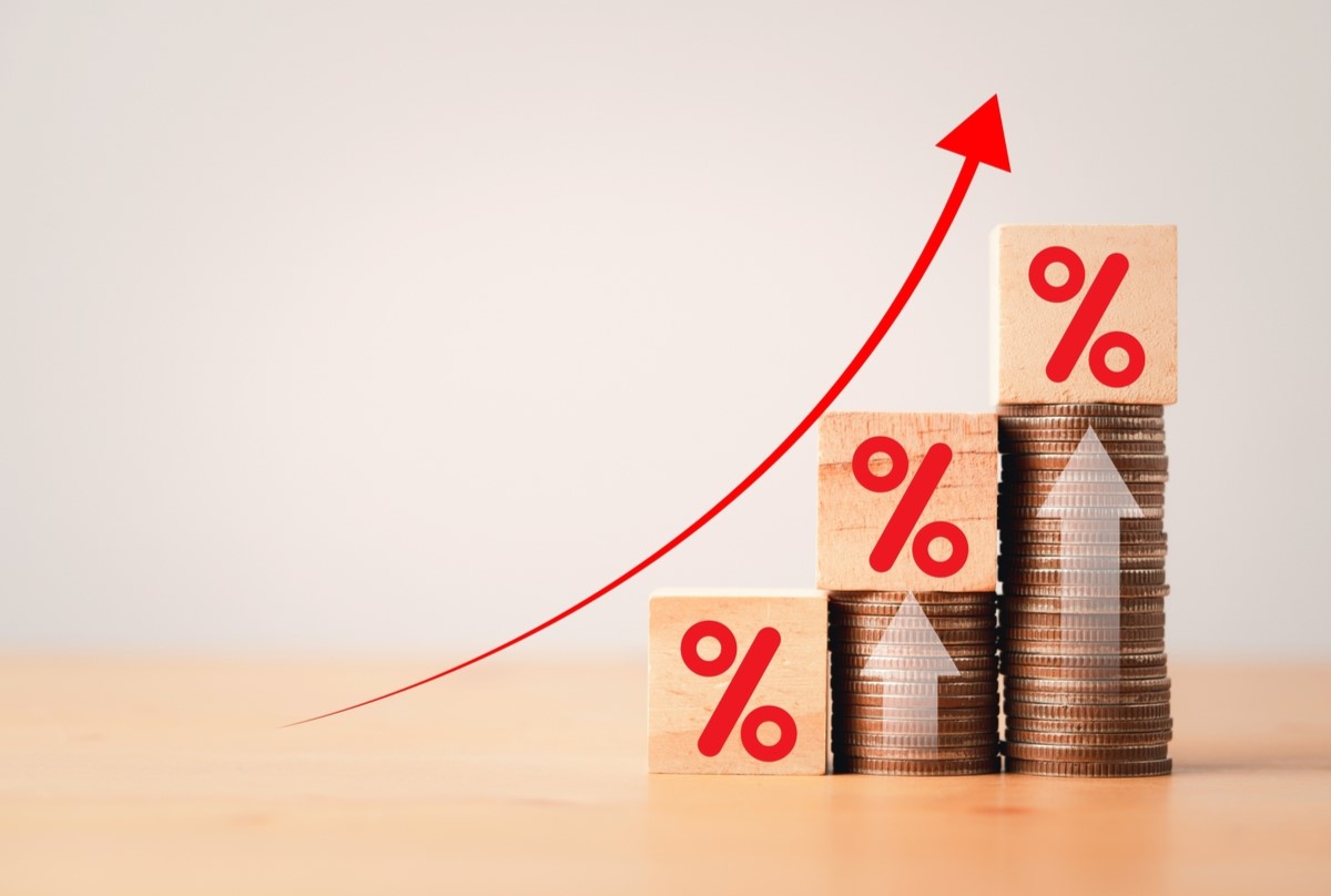 コインの上に積まれた木のブロックと上昇する矢印、投資利益の成長を表現。