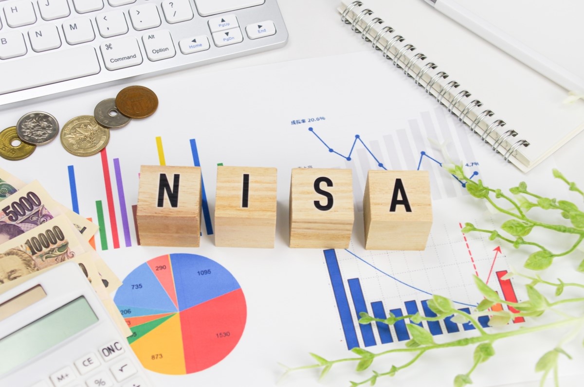 NISAのブロック文字と投資グラフ、コイン、日本円の紙幣。