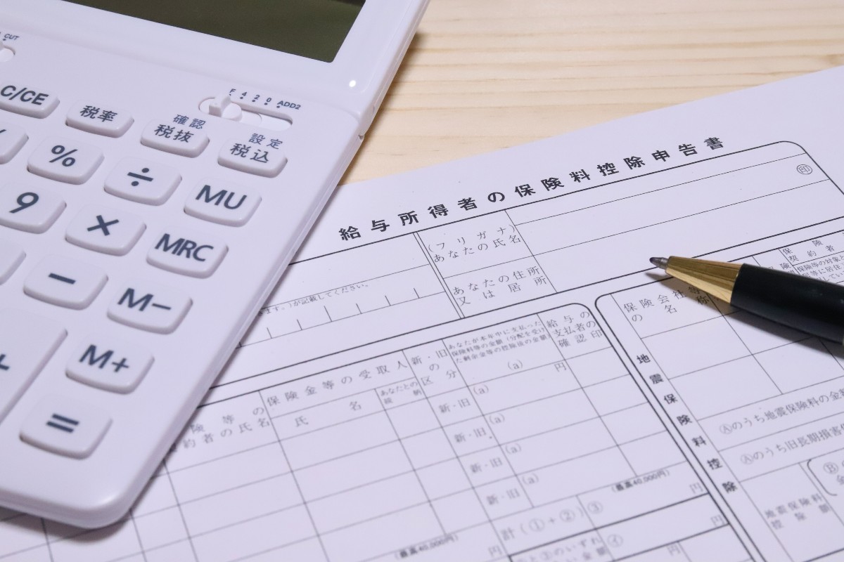 電卓と保険料控除申告書、ペンがデスクに置かれている。
