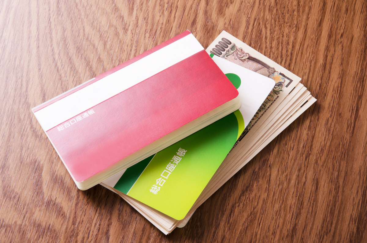 机の上に置かれた通帳と1万円札。