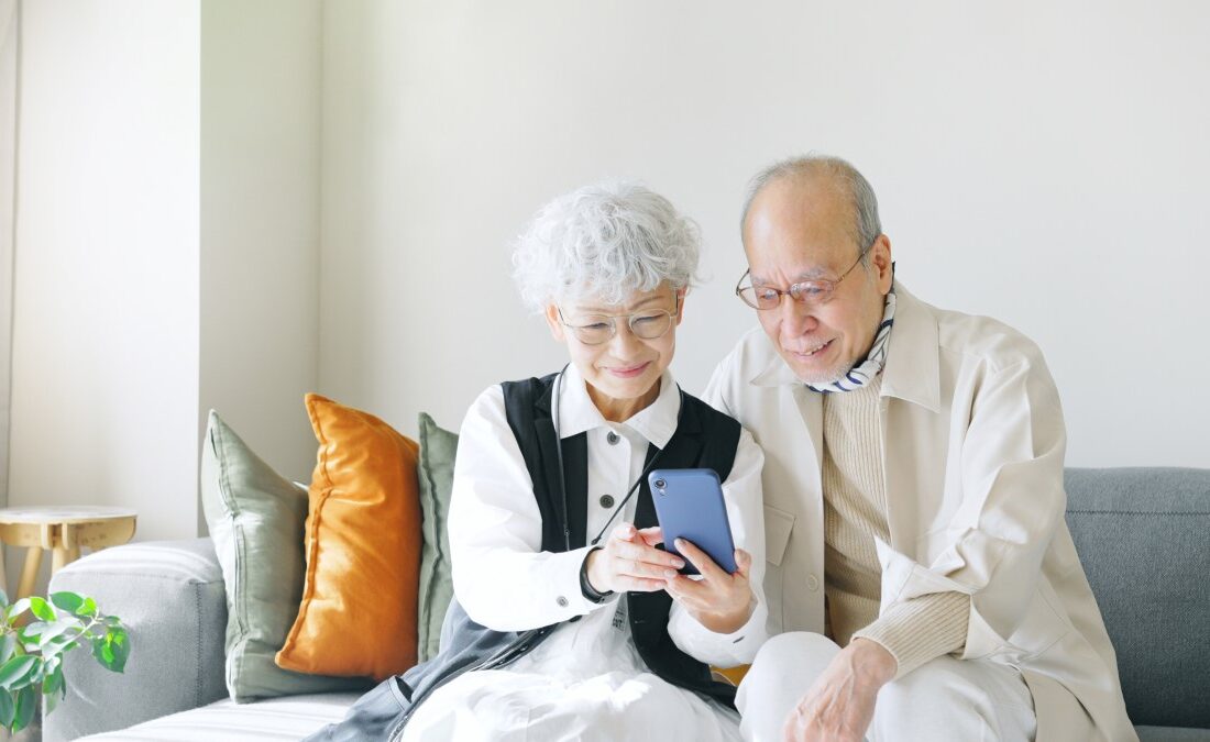 スマートフォンを一緒に見て微笑んでいる年配の夫婦