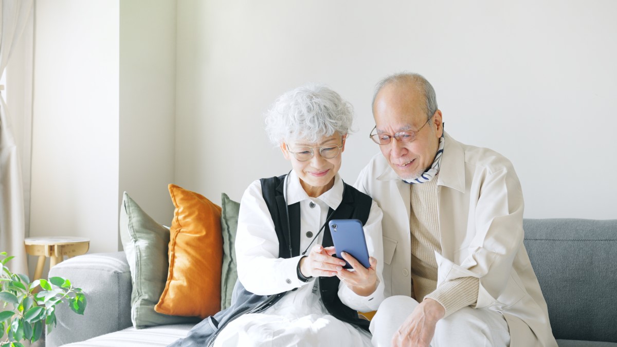 スマートフォンを一緒に見て微笑んでいる年配の夫婦
