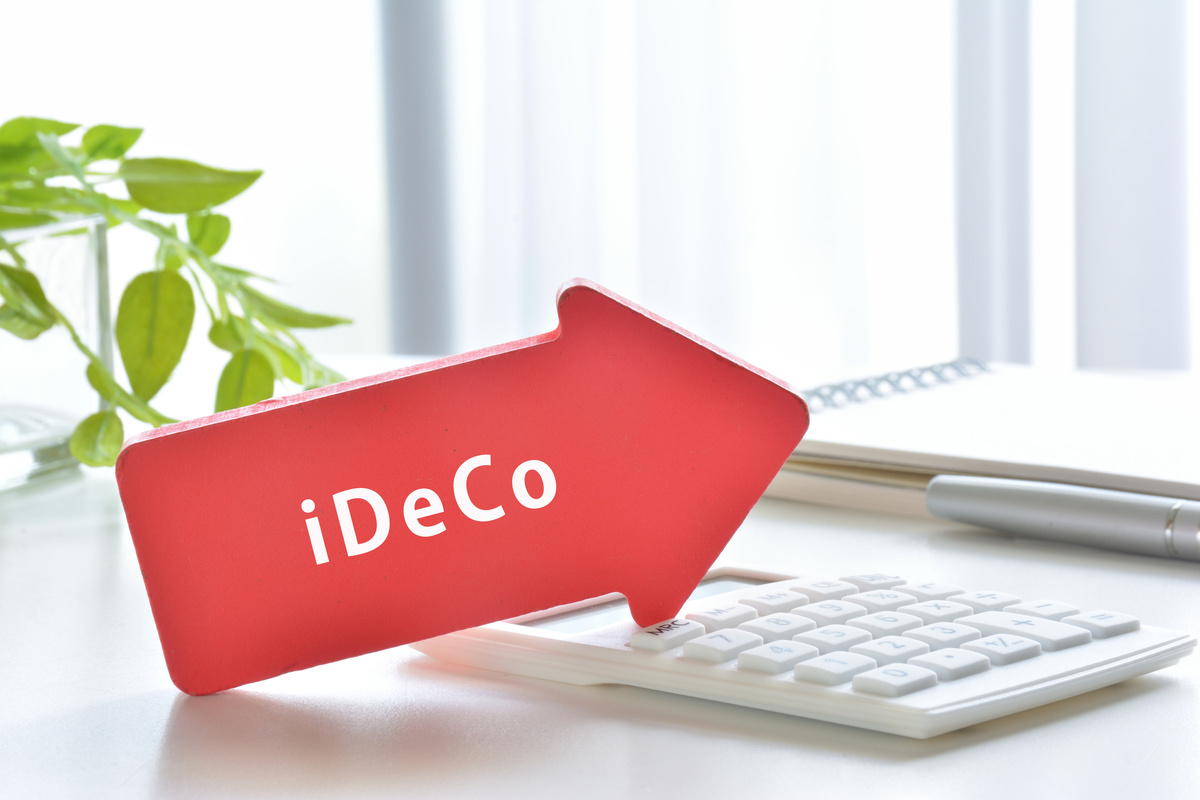 電卓の上に「iDeCo」と書かれた赤い矢印が置かれている。