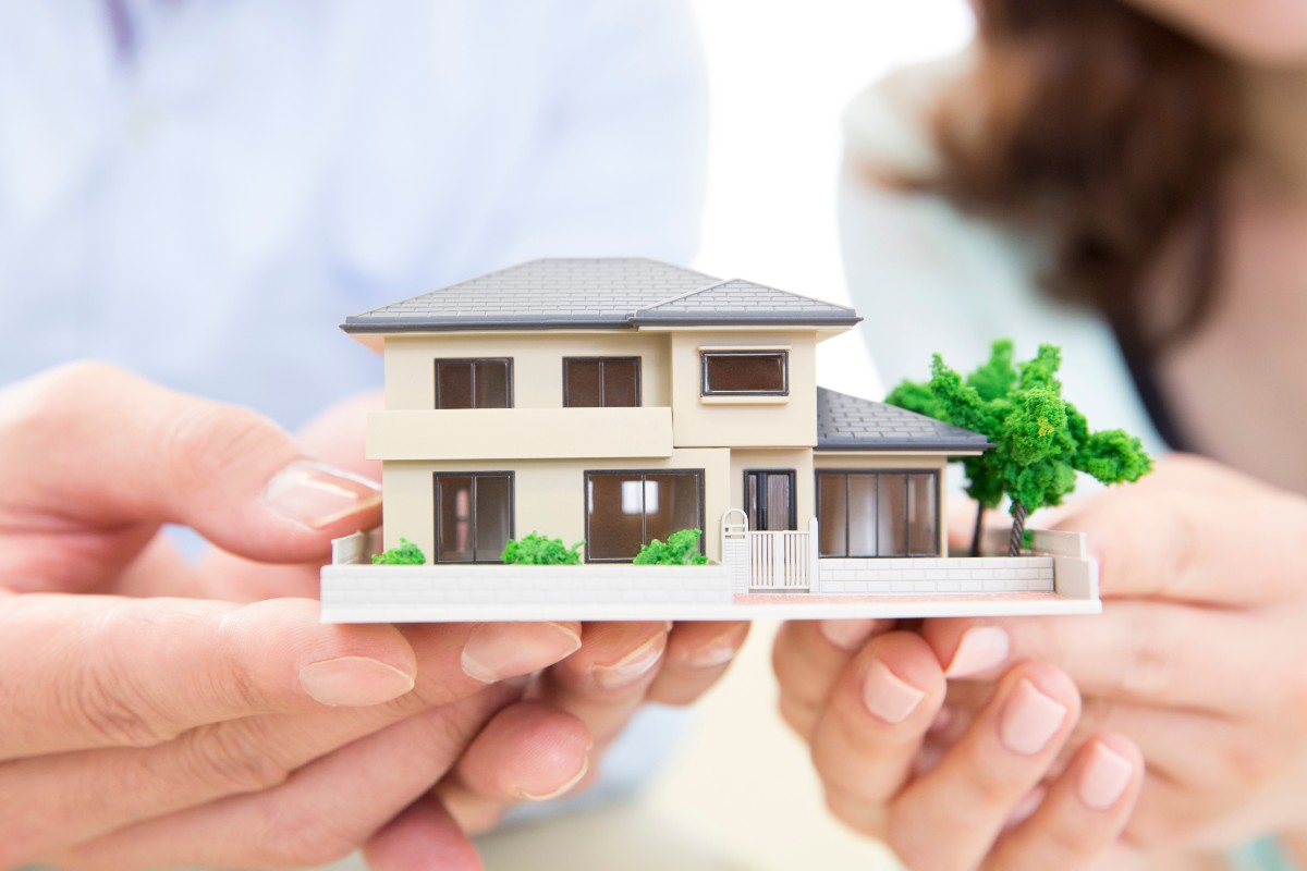 家の模型を手に持っている二人の人物の手元のアップ