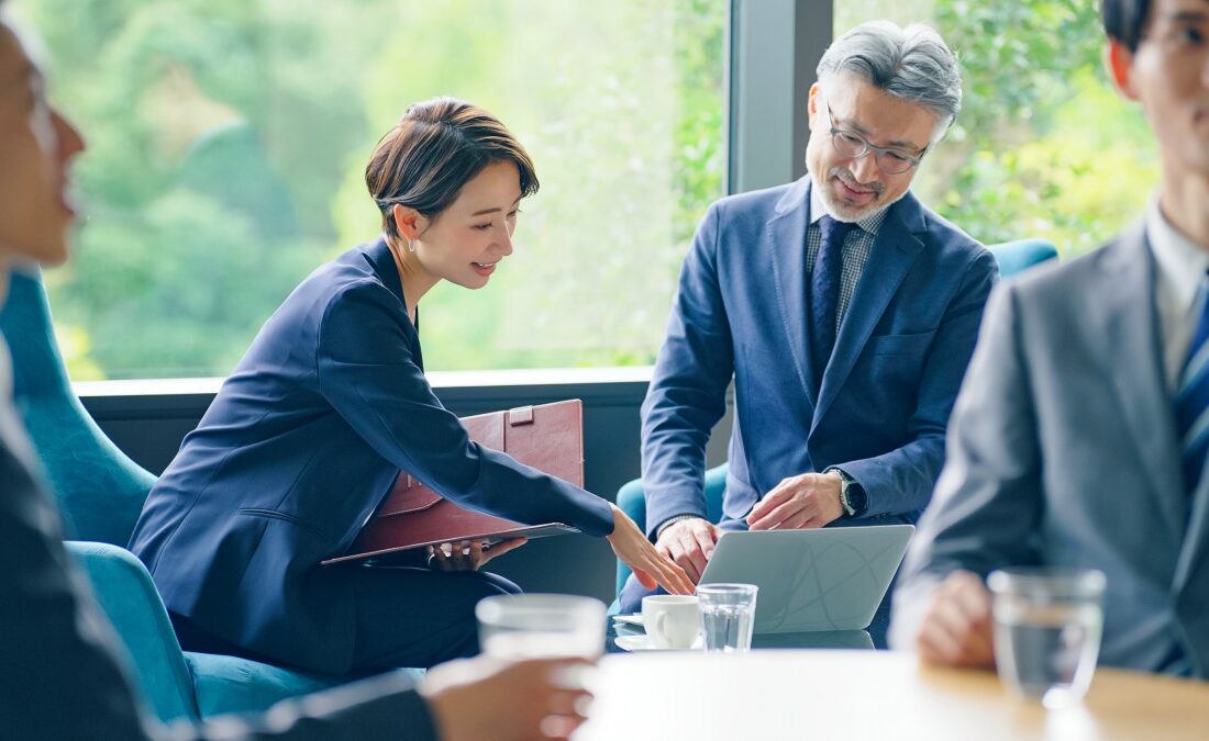 会議中のビジネスマンとビジネスウーマンがパソコンを見て話し合っている。