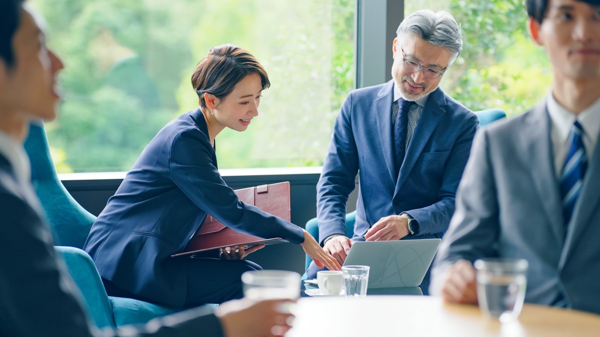 会議中のビジネスマンとビジネスウーマンがパソコンを見て話し合っている。