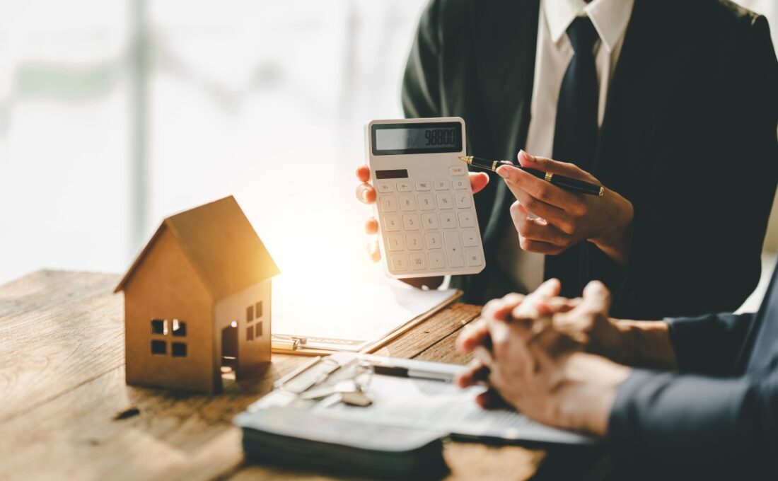 住宅模型、電卓、そして商談をしている二人の手元