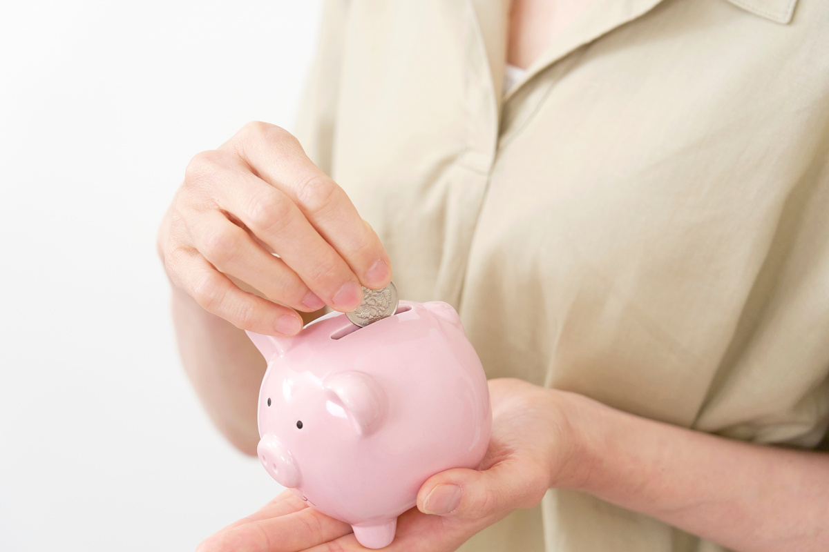 貯金箱に硬貨を入れている手
