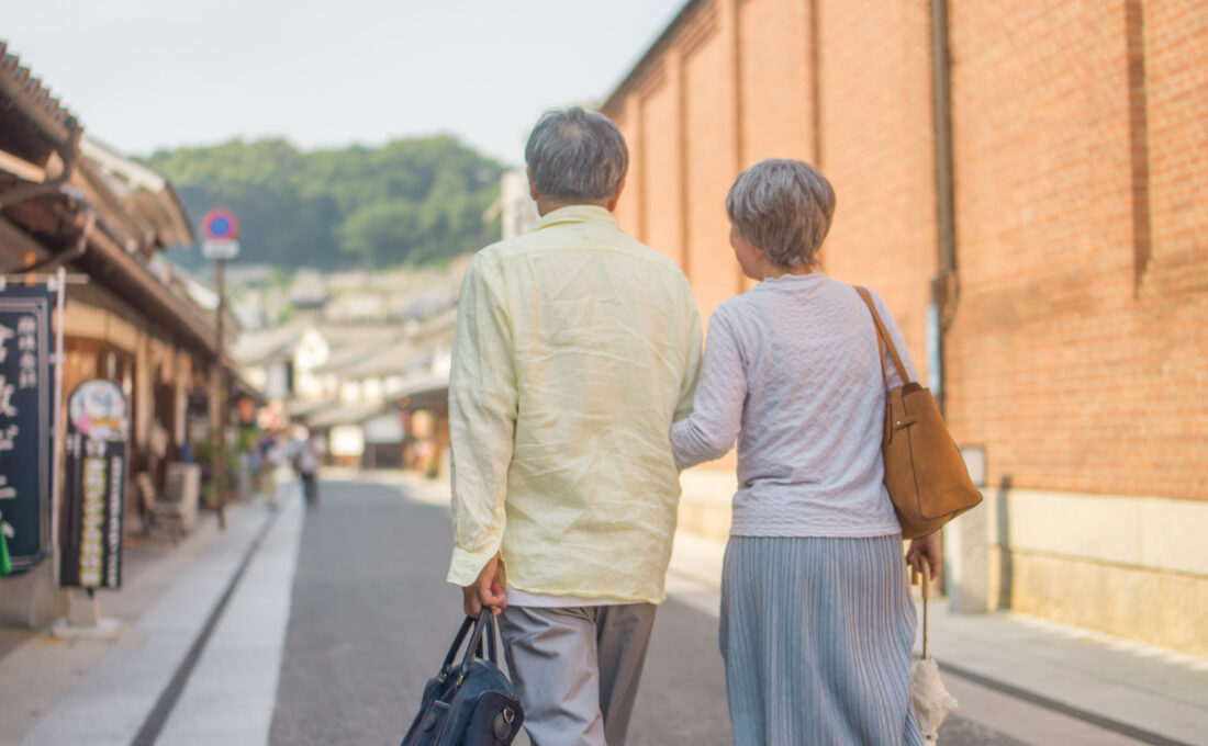 腕を組んで歩く年配の夫婦。
