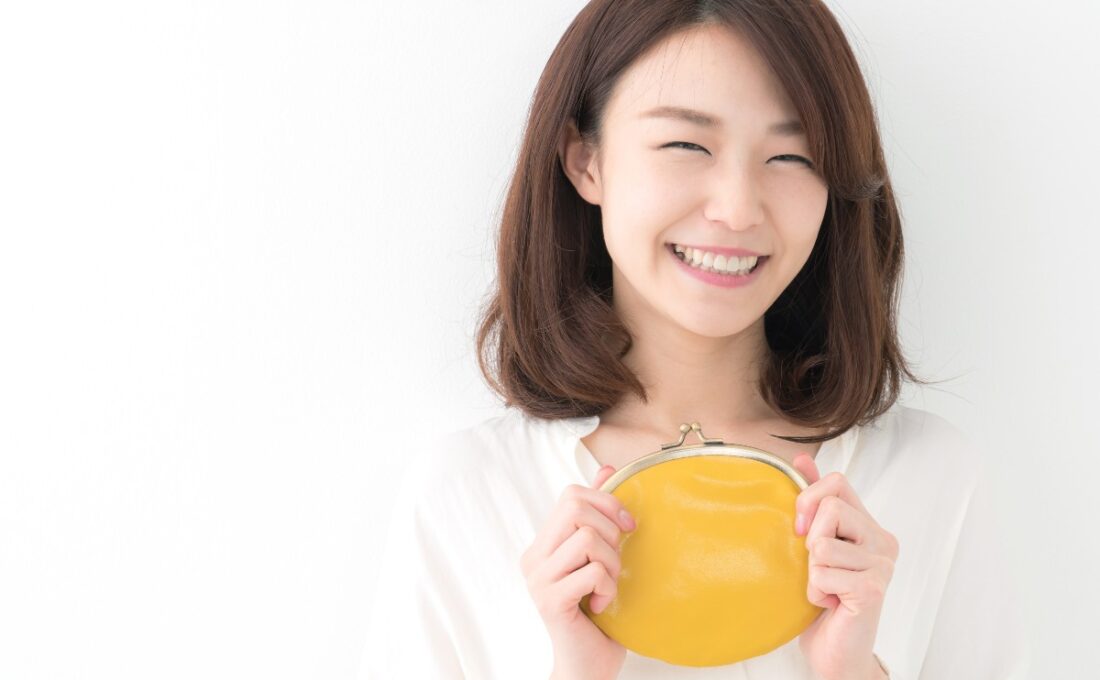 黄色い財布を持ち微笑む女性
