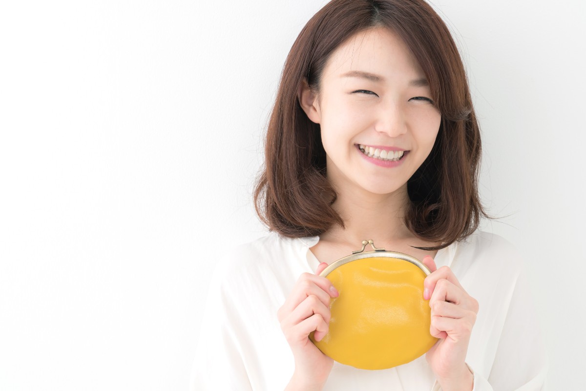 黄色い財布を持ち微笑む女性