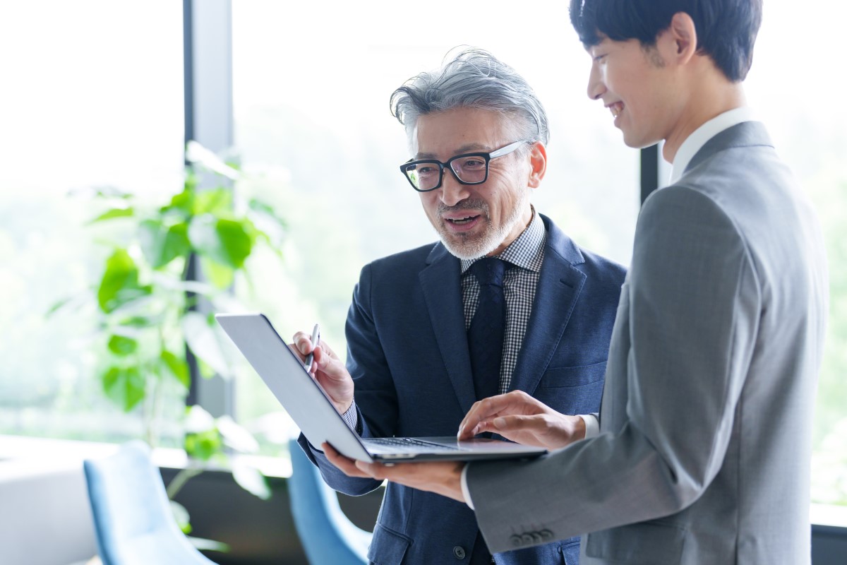 ノートパソコンを使ってビジネスミーティングを行う60代と20代の男性