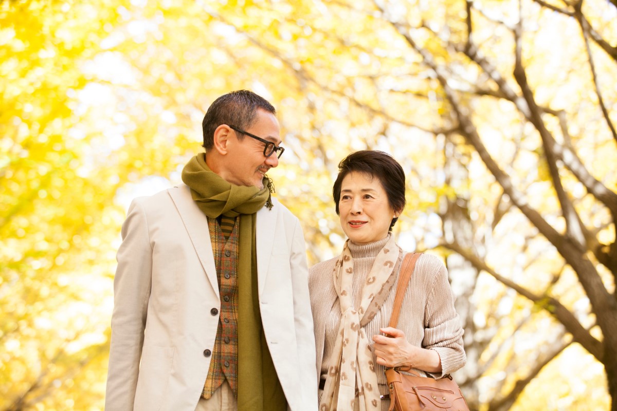 秋の紅葉の中を仲良く歩く高齢夫婦