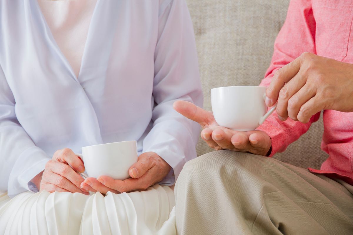 ソファでお茶を楽しむ高齢の夫婦。