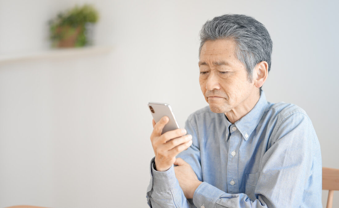 スマートフォンを見つめる年配の男性。