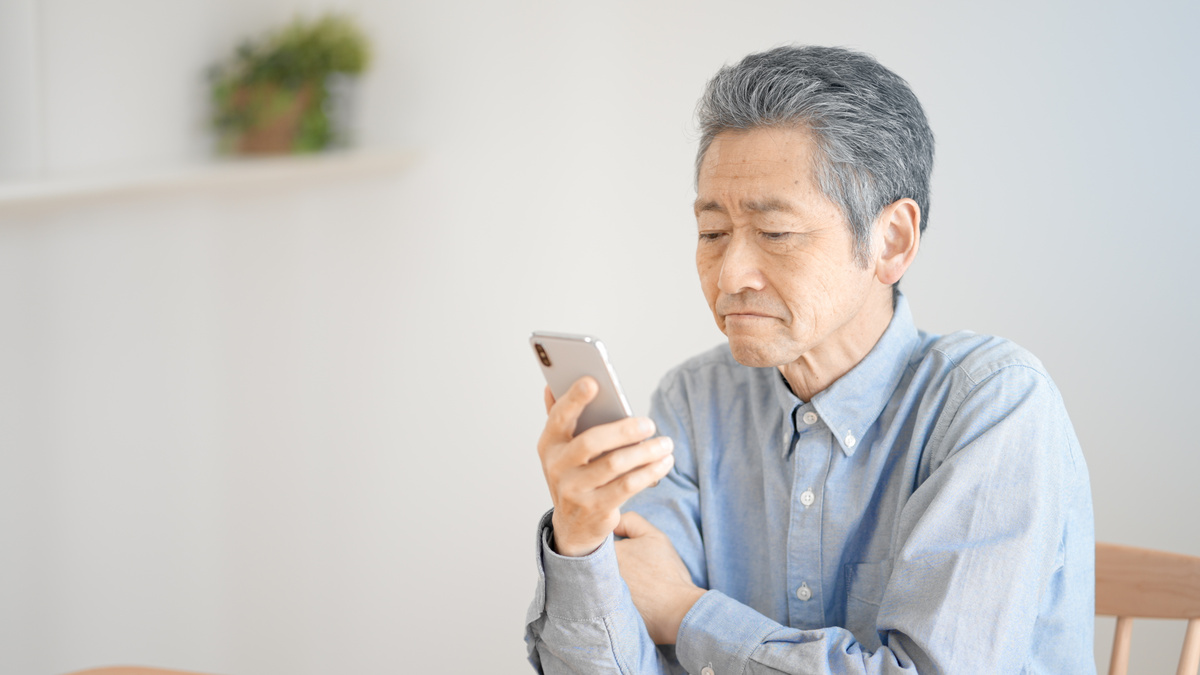 スマートフォンを見つめる年配の男性。