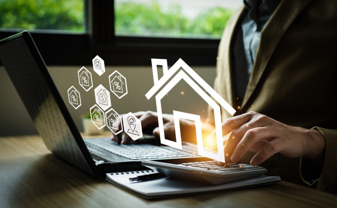 ノートパソコンで家に関する情報を入力しているビジネスマンと浮かび上がる家のアイコン