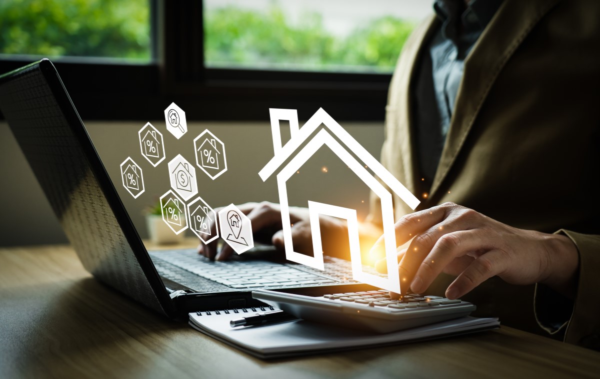 ノートパソコンで家に関する情報を入力しているビジネスマンと浮かび上がる家のアイコン