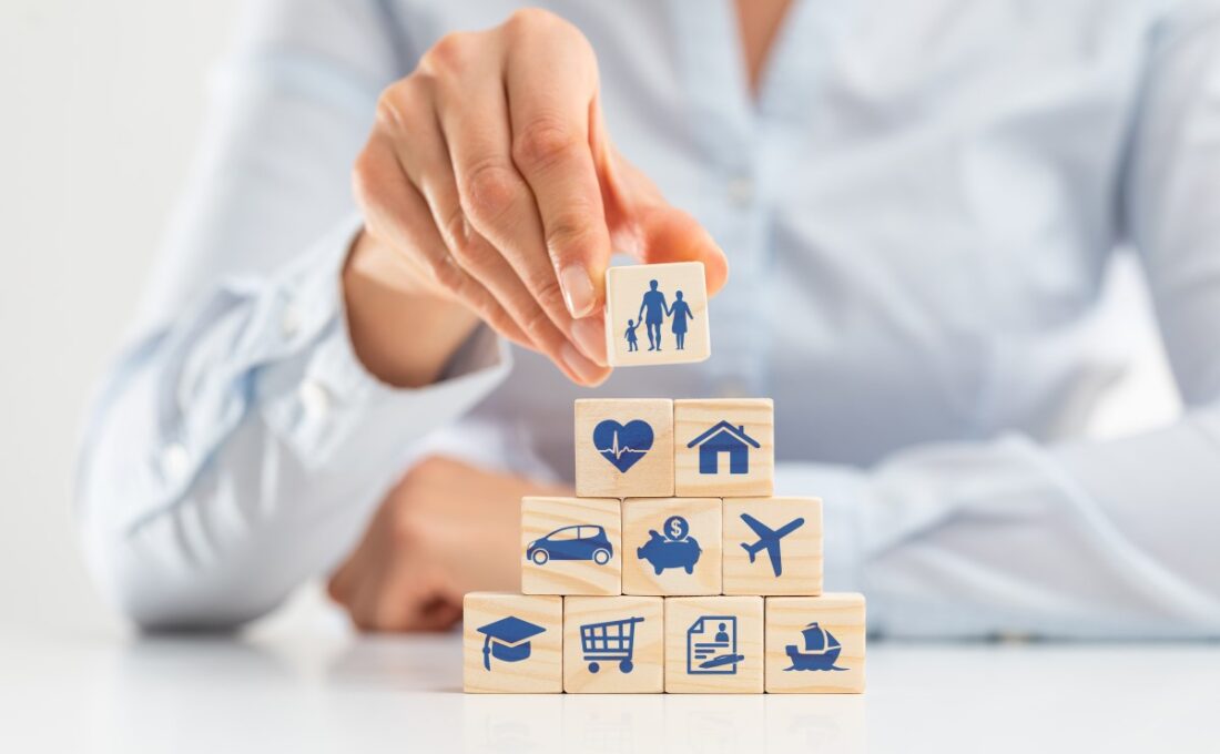 家族、健康、家、車などのアイコンが描かれた木製ブロックを積み上げている手